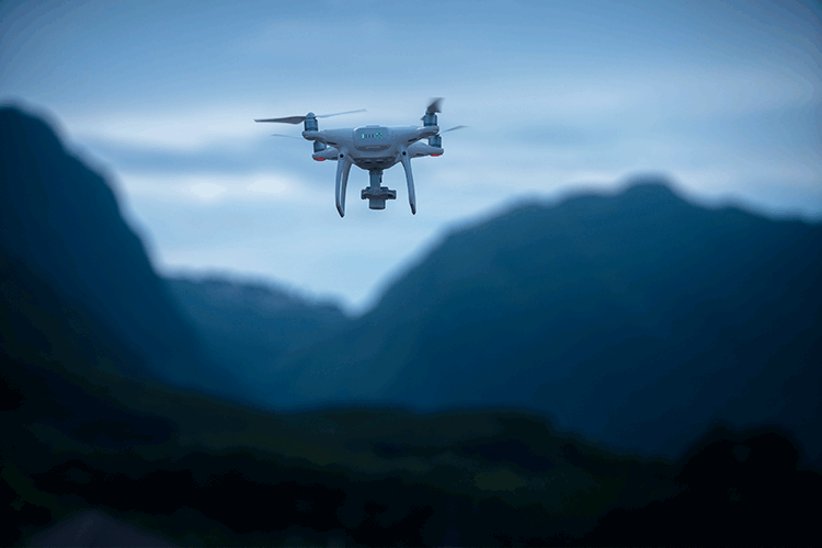 photograph of a drone flying above mountains