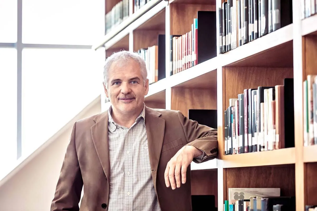 Man standing beside a bookshelf in a library