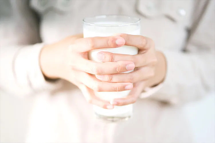 Hands of a girl holding a glass of milk