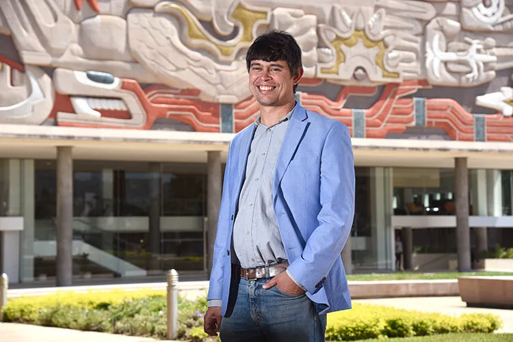 Man with blue jacket poses in front of a mural