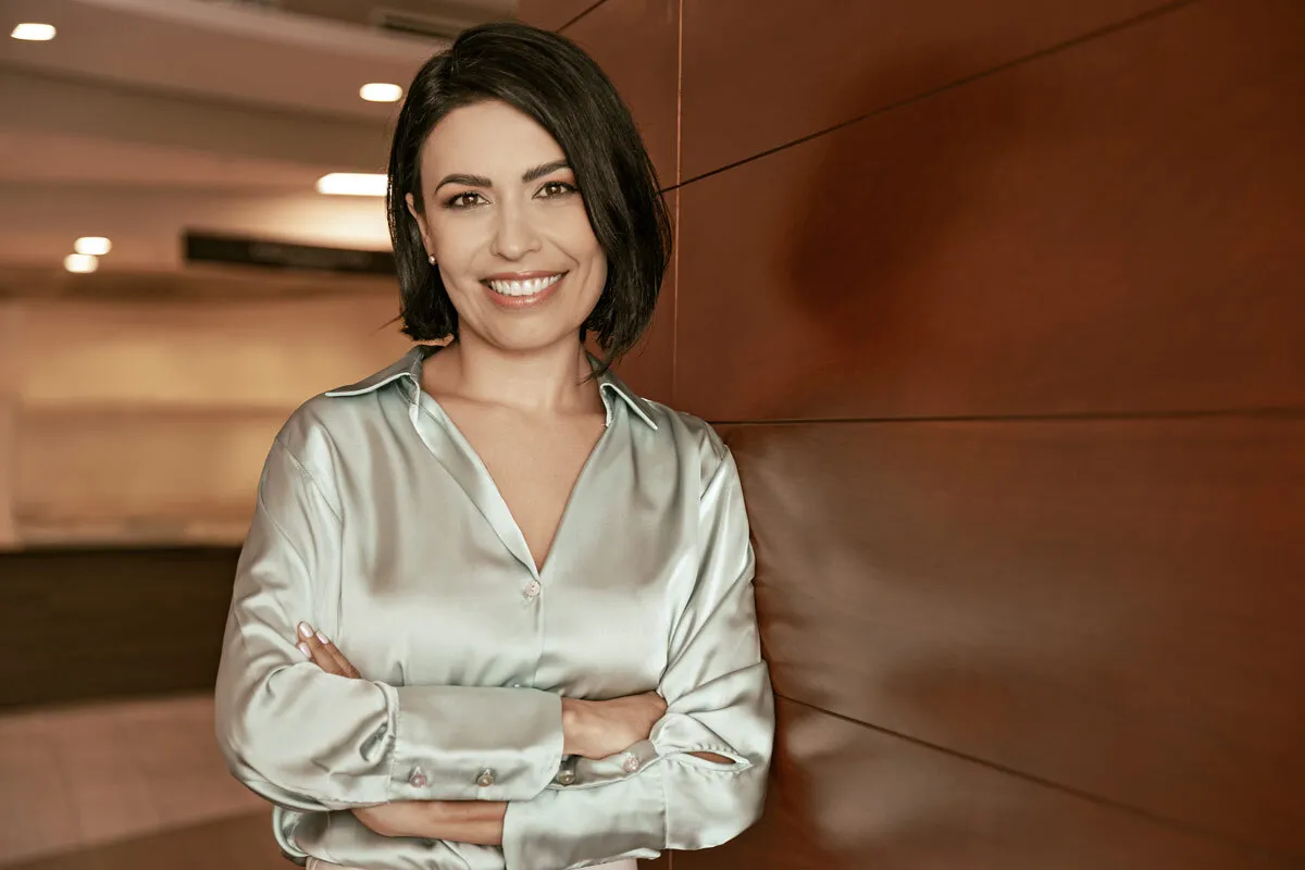 Woman with a nice beige blouse, smiling and crossing arms