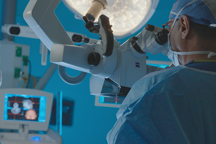 Photograph of a surgeon looking through a robotic microscope