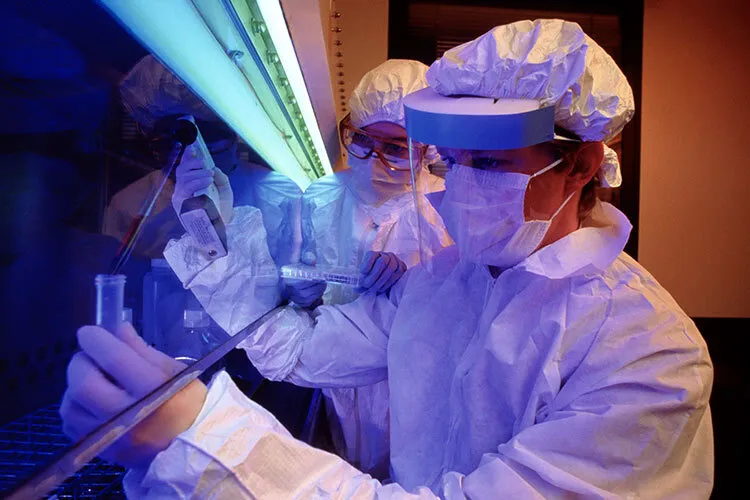 Photograph of a scientist dressed in protective equipment in an extraction hood