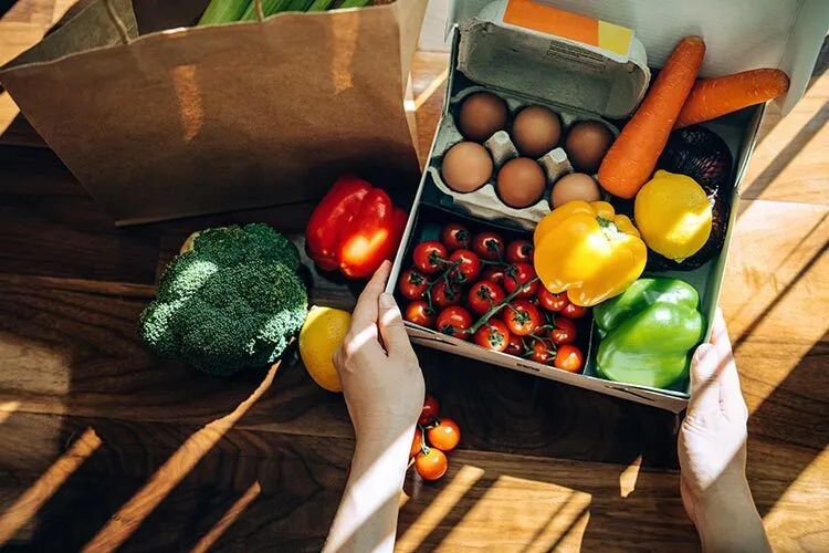 Photograph of a table with fresh vegetables, fruits and eggs.