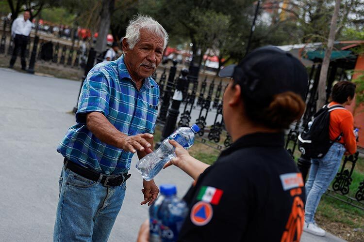 a civil protection agent gives a bottle of water
