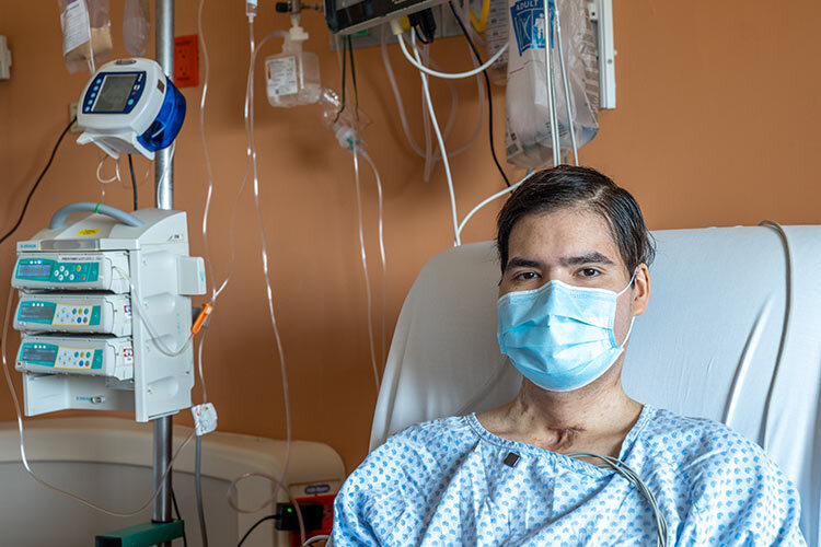 Photograph of a patient wearing a face mask in a hospital bed