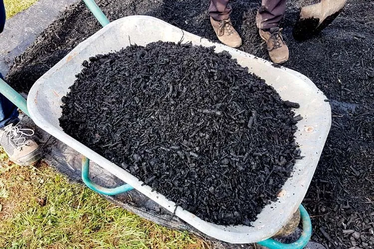 The image shows a wheelbarrow full of charcoal.