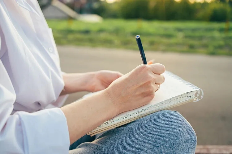 a photograph of a person writing in a diary