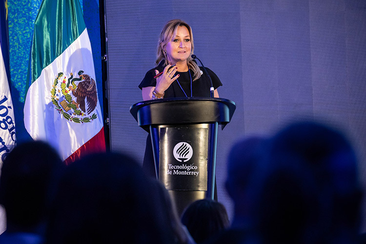 Photo of a woman, Angélica Pongutá, on a podium speaking into a microphone