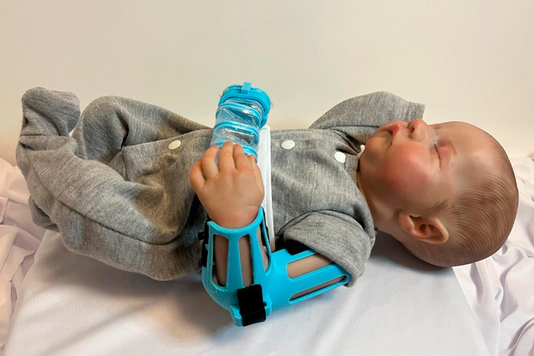 Prototype of the DINA robot placed on the arm of a neonatal simulation doll to demonstrate its operation.