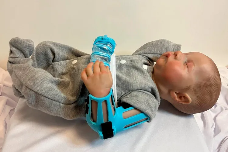 Prototype of the DINA robot placed on the arm of a neonatal simulation doll to demonstrate its operation.