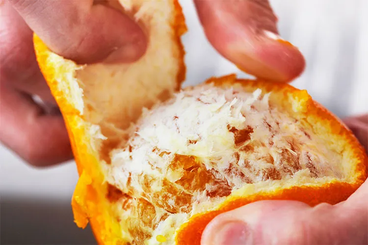 A hand peels an orange