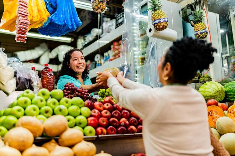 A woman shops for fruit at a stand in a local market.