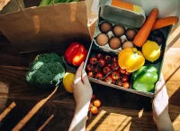 Photograph of a table with fresh vegetables, fruits and eggs.