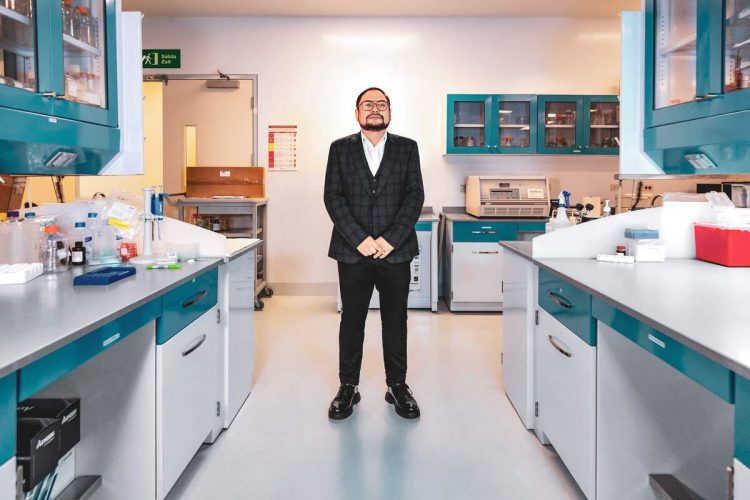 Man wearing a blue suit standing in the middle of a laboratory