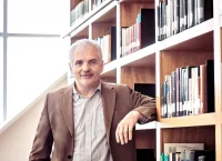 Man standing beside a bookshelf in a library