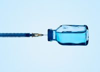A syringe and a blue liquid in a vaccine bottle