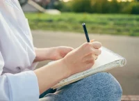 a photograph of a person writing in a diary