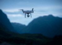 photograph of a drone flying above mountains