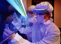 Photograph of a scientist dressed in protective equipment in an extraction hood