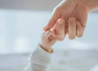 imagen de un dedo de un niño agarrando la mano de un adulto