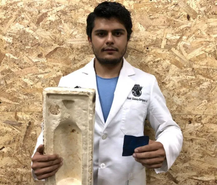 Hombre tez morena y cabello negro visitiendo una bata blanca y sosteniendo empaques