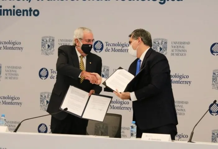 Dos hombres de edad mediana, vistiendo traje, se saludan