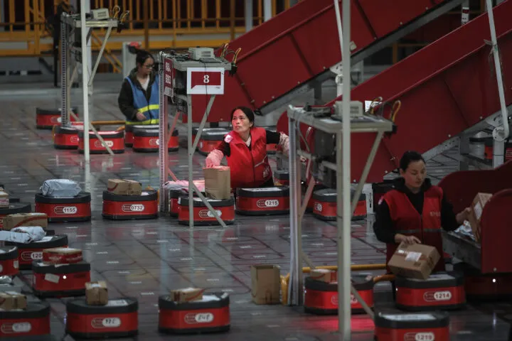Foto de una línea de producción automatizada con varios robot y tres personas en la operación