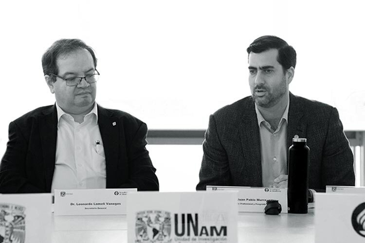 Dos hombres sentados en un panel de una conferencia