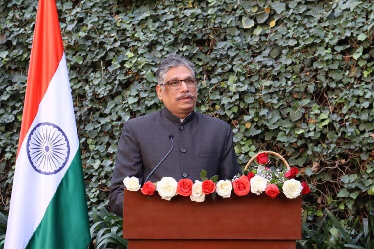 Hombre dando un discurso con la bandera de India detras.