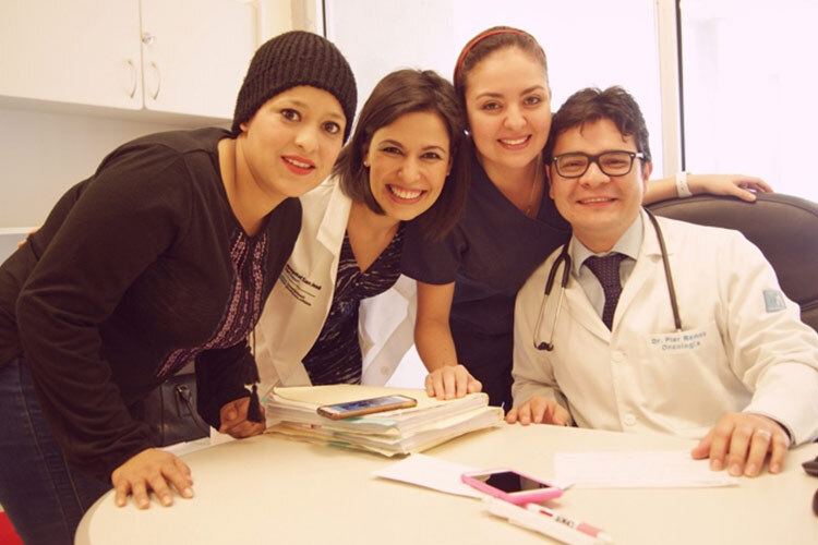 una imagen donde 3 médicos rodean a una paciente que venció el cancer