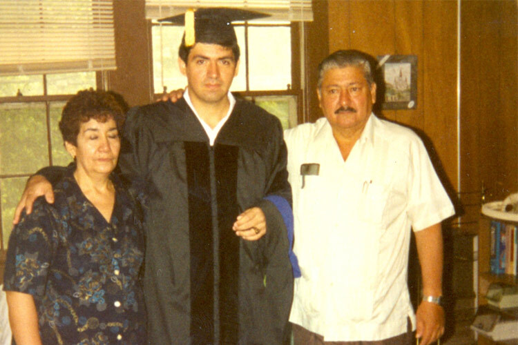 Hombre joven con su traje de graduado y alrededor de él, sus padres