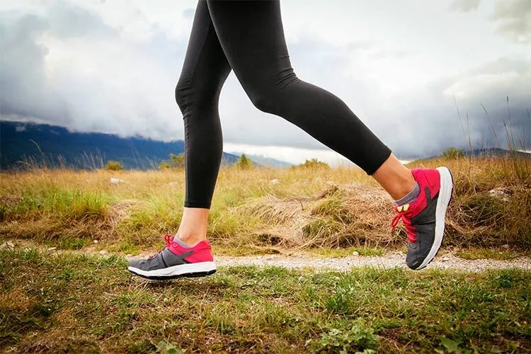 Foto donde se ven las piernas de una mujer corriendo en el campo