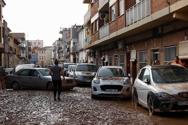 Una persona camina junto a coches dañados a lo largo de una calle cubierta de barro después de que las lluvias torrenciales causaran inundaciones en Guadassuar, región de Valencia. (Foto: Reuters)