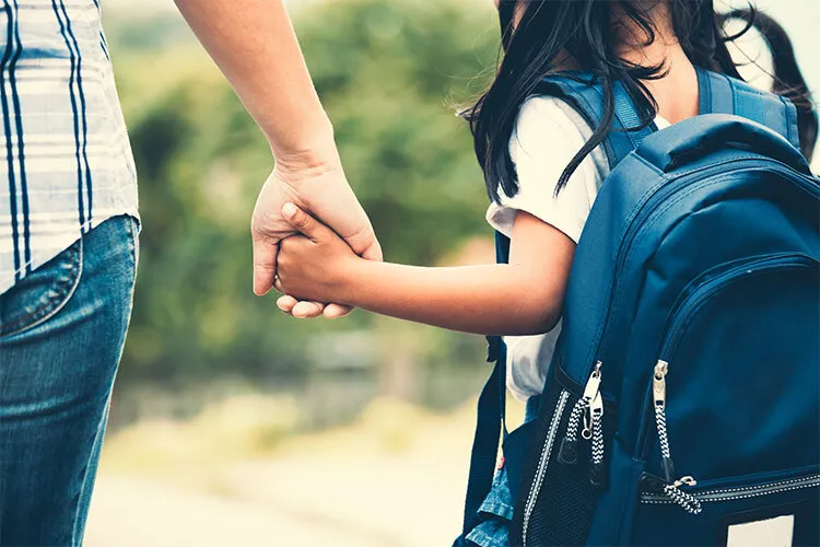 una niña tomada de la mano de un adulto
