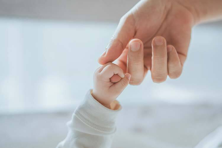 imagen de un dedo de un niño agarrando la mano de un adulto