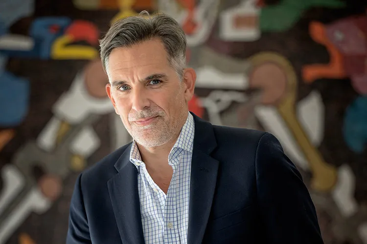 imagen de un hombre con barba, saco negro y camisa azul