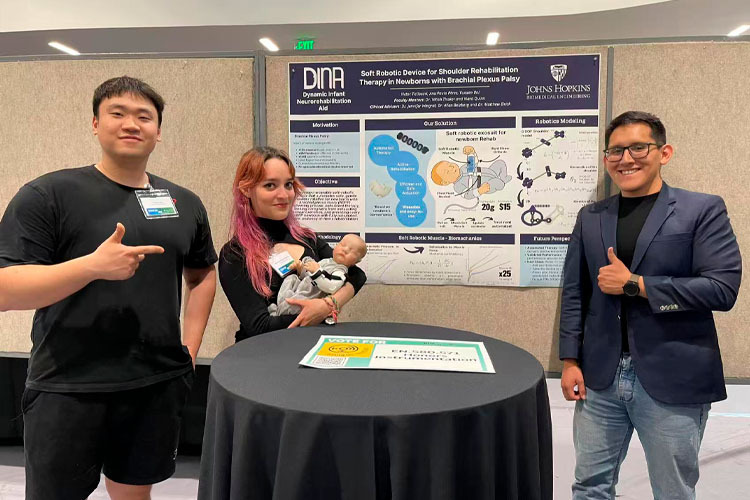 Integrantes del equipo DINA presentan el prototipo del robot suave para rehabilitación de recién nacidos frente a su póster académico.