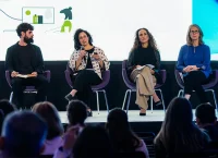 Fotografía de un hombre y tres mujeres sentadas en un escenario discutiendo