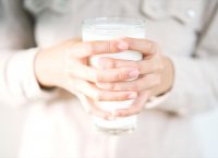 Manos de una niña agarrando un vaso de leche