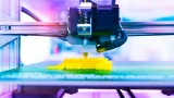 fotografia de una impresora 3D imprimiendo algo amarillo