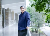 Hombre de mediana edad con camisa azul recargado en un barandal