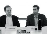 Dos hombres sentados en un panel de una conferencia