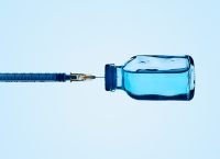 Una jeringa y una vacuna con líquido azul