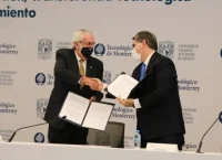 Dos hombres de edad mediana, vistiendo traje, se saludan