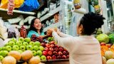 un puesto de fruta donde se ve a una mujer comprando