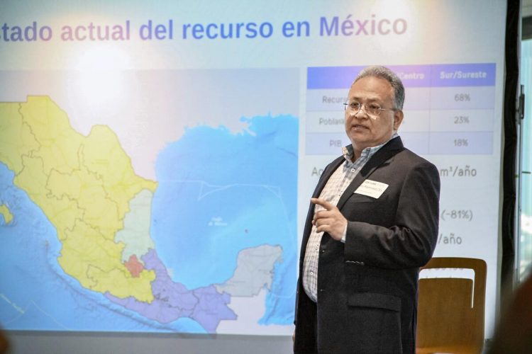 Especialista en tema del agua explica una presentación sobre este tema proyectada con un mapa de México detrás de él.