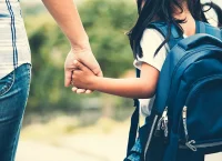 una niña tomada de la mano de un adulto