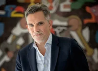 imagen de un hombre con barba, saco negro y camisa azul