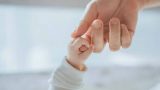 imagen de un dedo de un niño agarrando la mano de un adulto